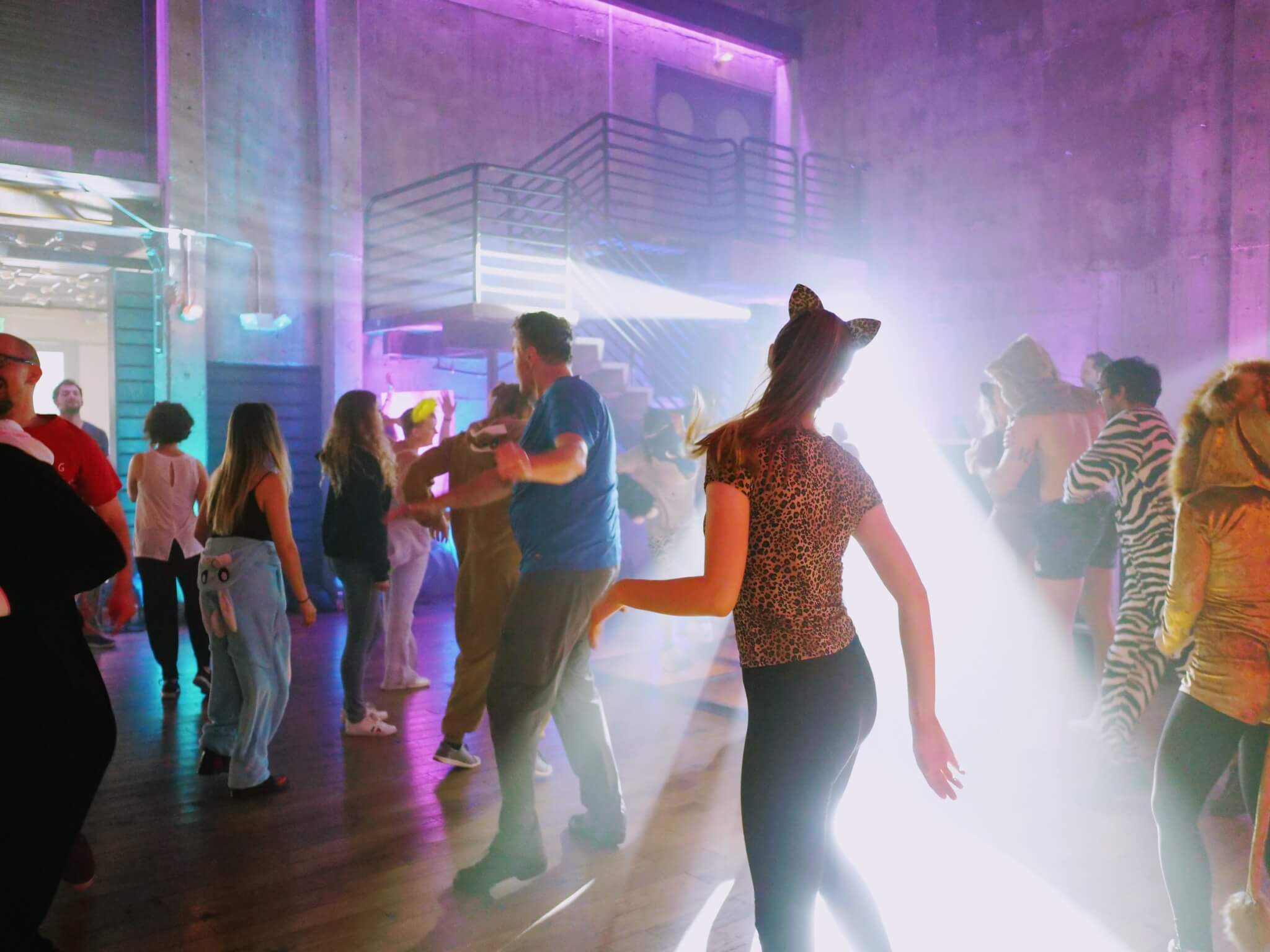 Cincinnati DJs leading a group of people dancing in a dark room.