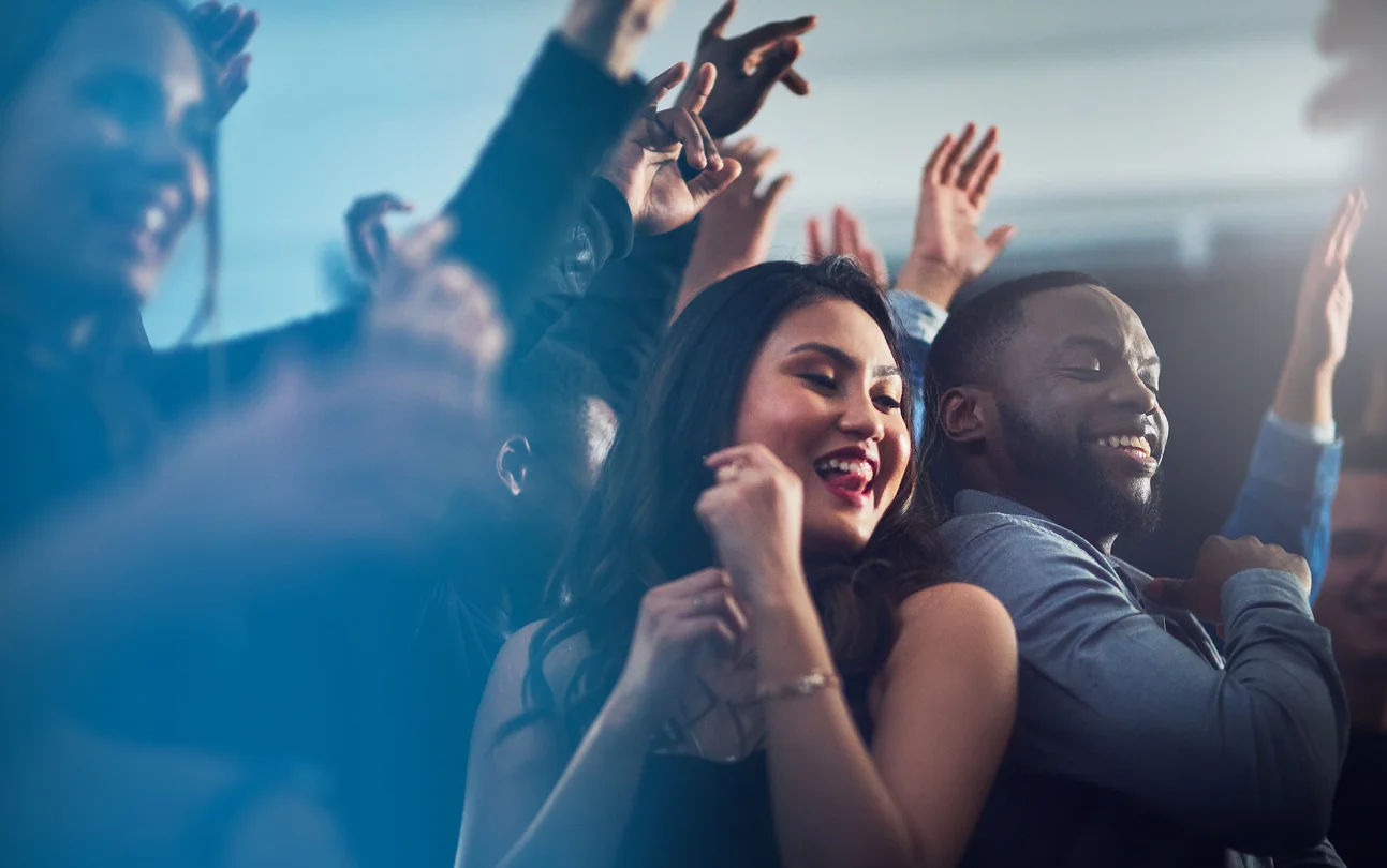 A group of people at a party with their hands up, celebrating with the best wedding DJs in Cincinnati.