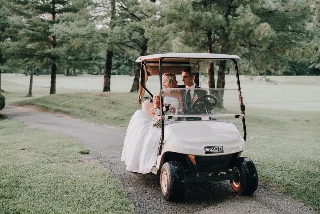 Bride and groom riding on a gold cart at Bel-Wood Country Club